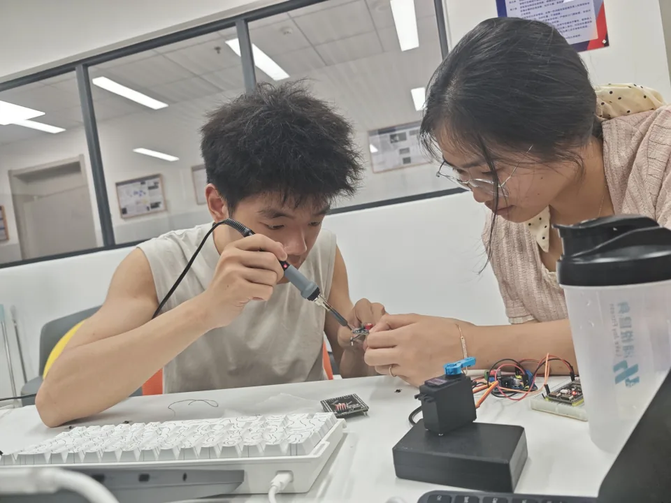 同学在桌边连接和调试电子元件